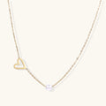Dainty 14K gold plated stainless steel necklace with an open heart charm and a single round white bead on a cream background.
